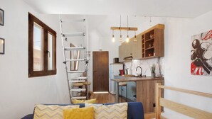 A compact living space with a sofa, a ladder, a kitchen area, and a dining table.