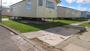 A single-story mobile home with a front porch and a small attached garage. - Hideaway Lodge (Abergele)
