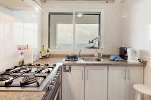 Una cucina con gas, un lavello, una finestra vista e una macchina per il caffè.