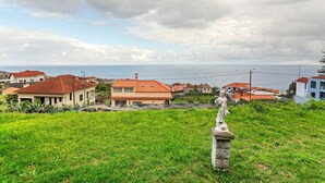 A coastal town with houses, a statue, and a view of the sea. - Holiday Home 'Blissful Haven - Soulful Stays' with Sea View, Private Terrace and Wi-Fi (Porto Moniz)