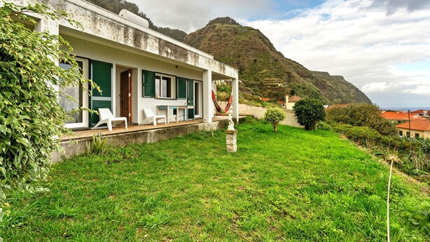 A white building with green shutters, a grassy lawn, and a mountain in the background. - Holiday Home 'Blissful Haven - Soulful Stays' with Sea View, Private Terrace and Wi-Fi (Porto Moniz)