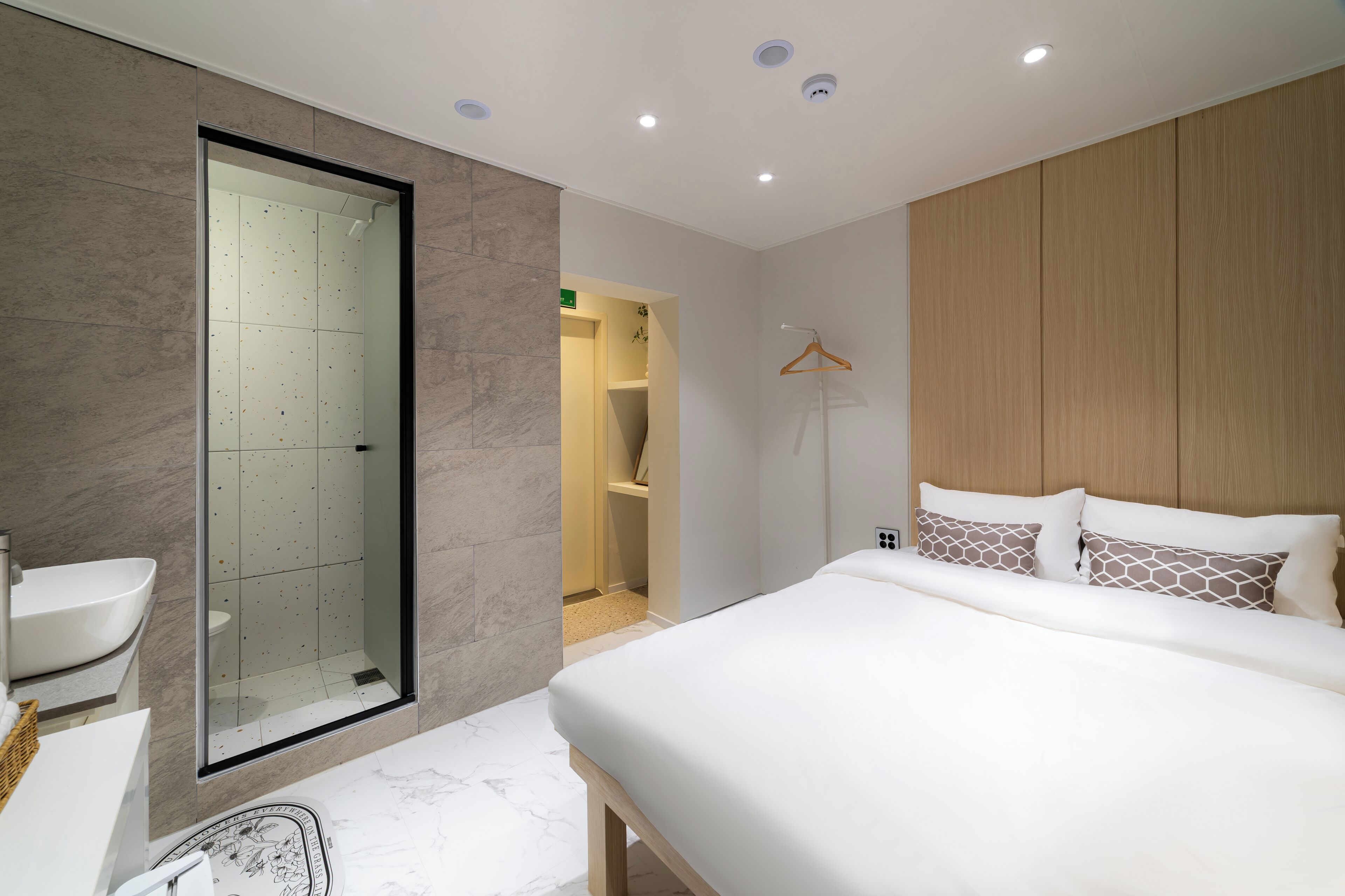 Een moderne hotelkamer met een groot bed, een douchecabine met glazen wanden en een apart badkamermeubilair.