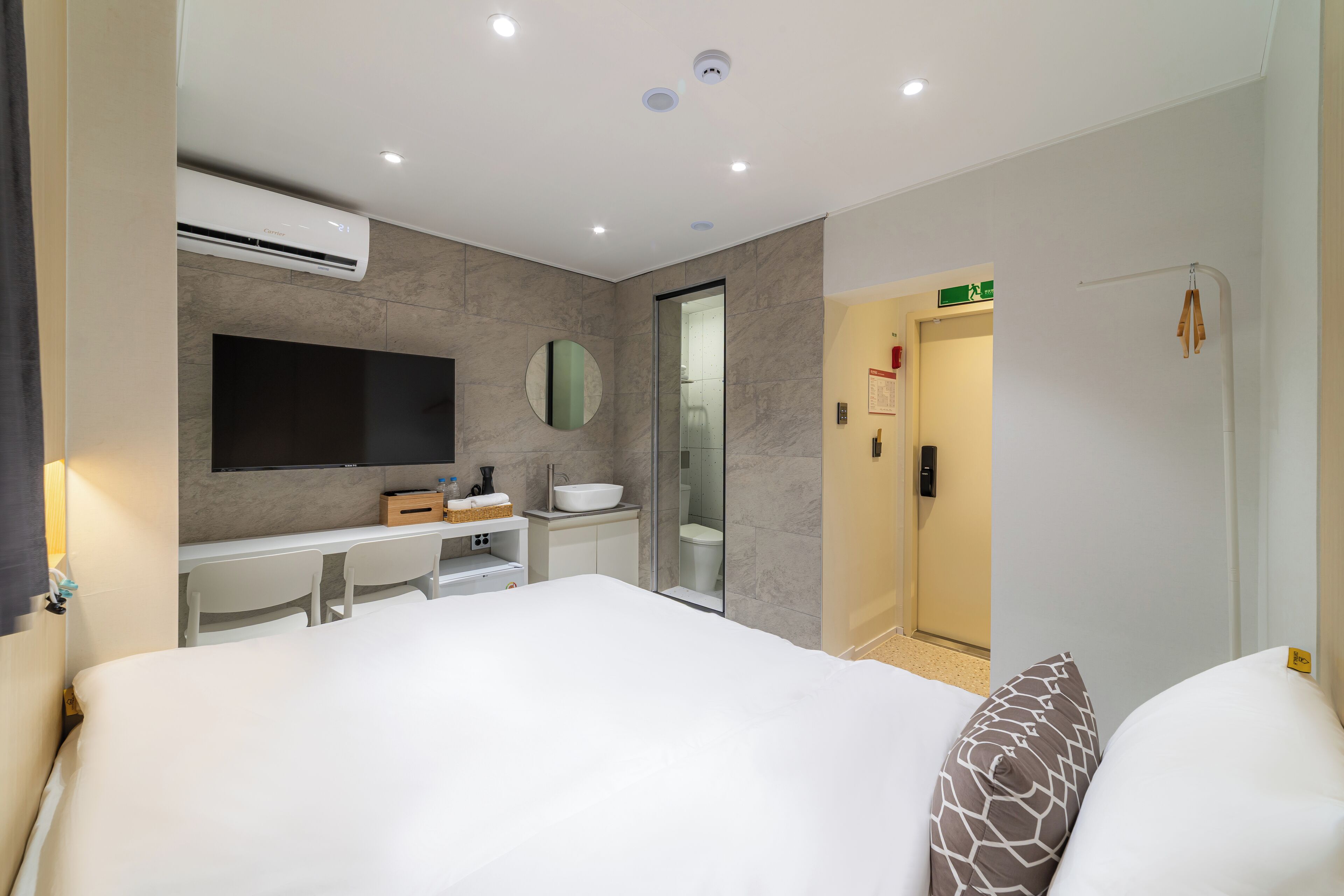 Una habitación de hotel moderna con una cama grande, un escritorio con lavamanos, un espejo y un televisor.