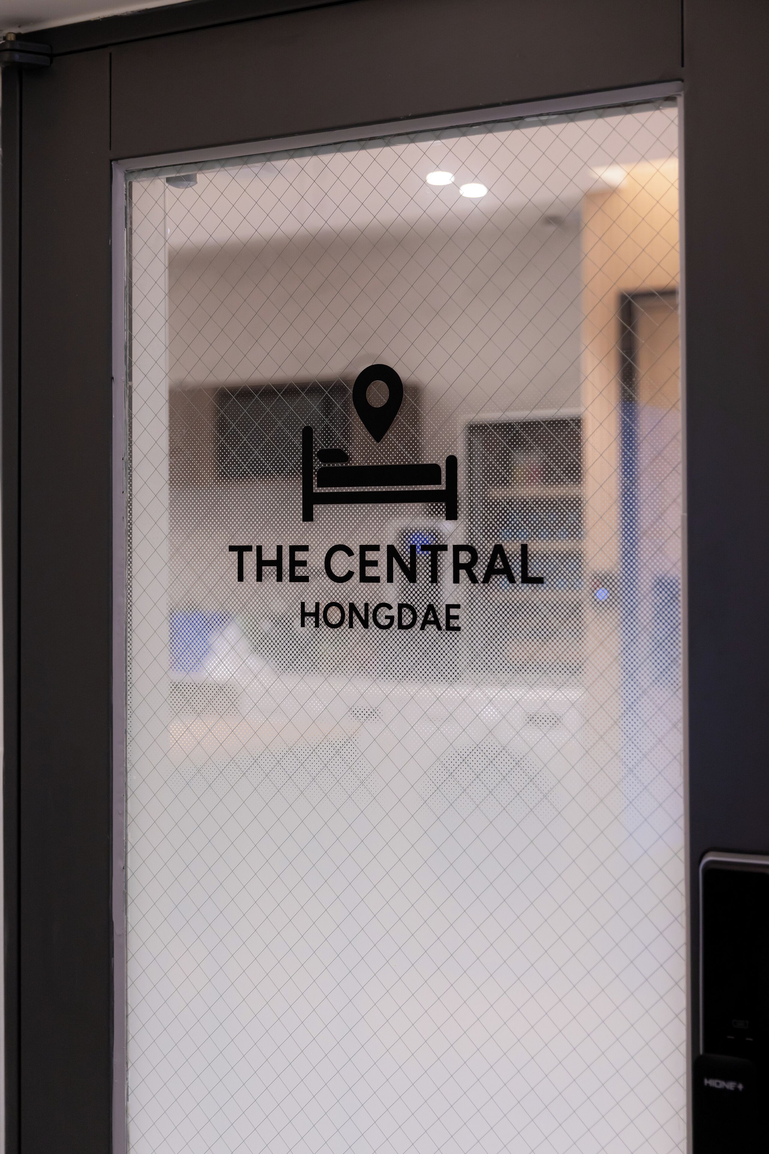 A glass door with a logo and text reading "The Central Hongdae".