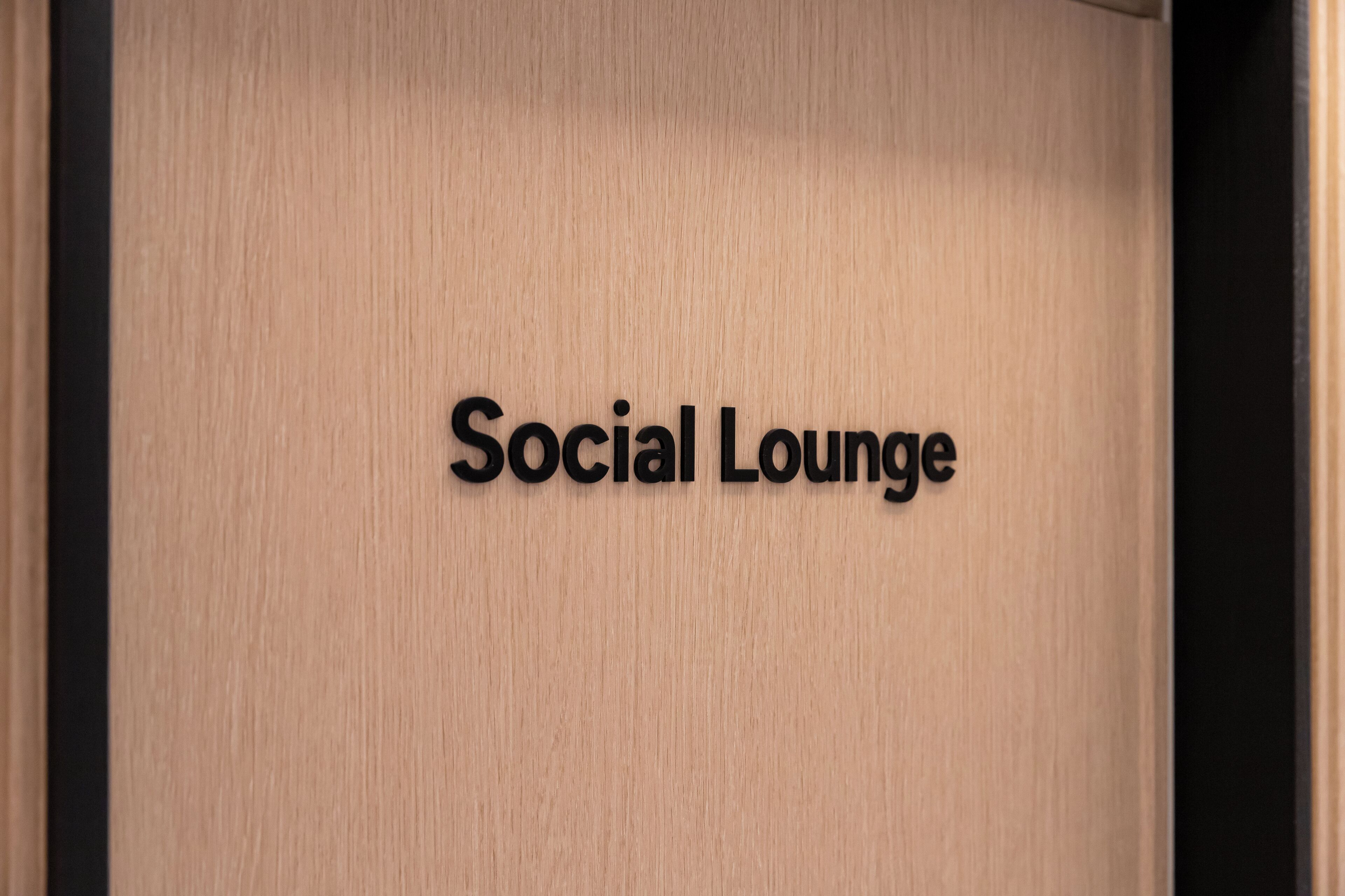 Un letrero con la inscripción 'Social Lounge' sobre una superficie de madera.