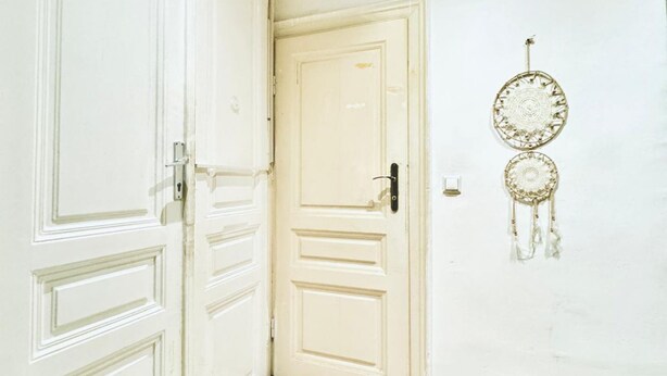 Una puerta blanca con una cerradura y un atrapasueños en la pared.