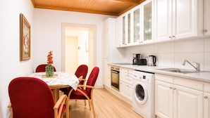 A kitchen with white cabinets, a washing machine, and a coffee maker. - Inviting Getaway Near FAC Platz (Vienna)