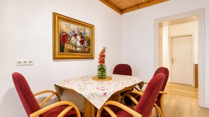 A dining area with a table set for four, surrounded by red upholstered chairs. A framed floral painting hangs above the table. - Inviting Getaway Near FAC Platz (Vienna)