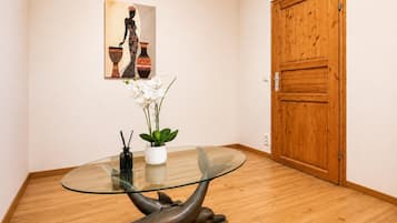 A room with a glass-top table, a dolphin sculpture, white orchids, and a wooden door.
