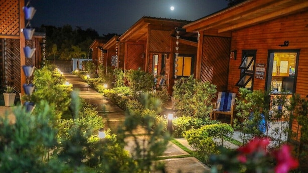 A row of wooden cabins with a pathway leading through a garden area. - Villa Dulce Refugio (Cabrera)