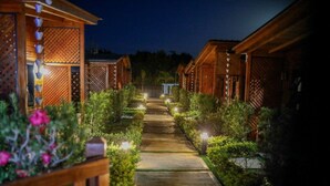 A pathway leading to wooden cabins with a garden on either side. - Villa Dulce Refugio (Cabrera)