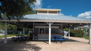 A covered outdoor patio with picnic tables and a bar area.