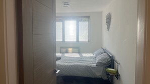 Ein Schlafzimmer mit einem Bett, einem Heizkörper, einem Fenster mit Jalousien und einer Wanddekoration.
