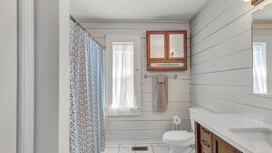 A bathroom with a toilet, a sink, a mirror, and a shower curtain.