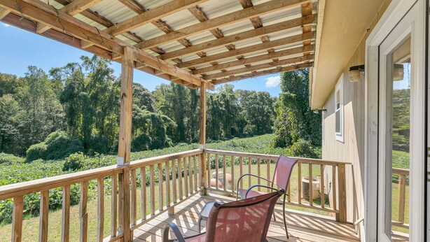 A wooden deck with a pergola, a table, and two chairs.
