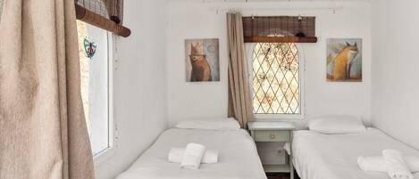 A room with two beds, a window with a view, and a painting of a fox.