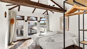 Ein Zimmer mit einem Bett, einem Fenster, einer Lampe und einem Holzregal.