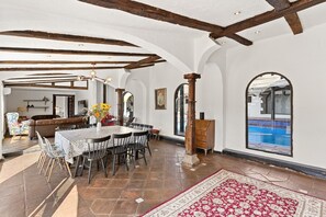 Un comedor con una mesa, sillas y vistas a una piscina.