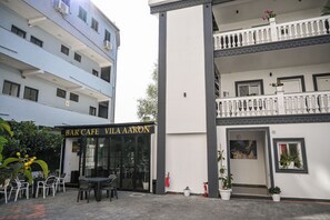 Un bar cafetería llamado "Vila Aaron" con terraza y un edificio de dos plantas con balcones.