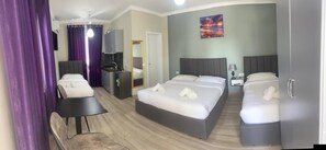 A hotel room with two beds, a desk, a chair, a small kitchenette, and a bathroom. - Hotel Vila Aaron (Durrës)