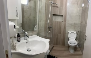 Een moderne badkamer met een wastafel, spiegel, toilet en douche.