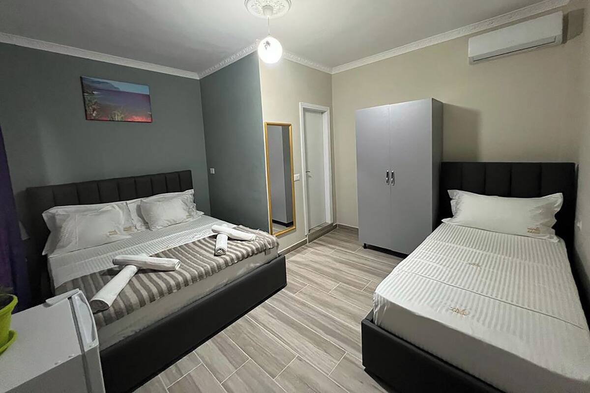 A hotel room with two beds, a wardrobe, a mirror, and a ceiling light.