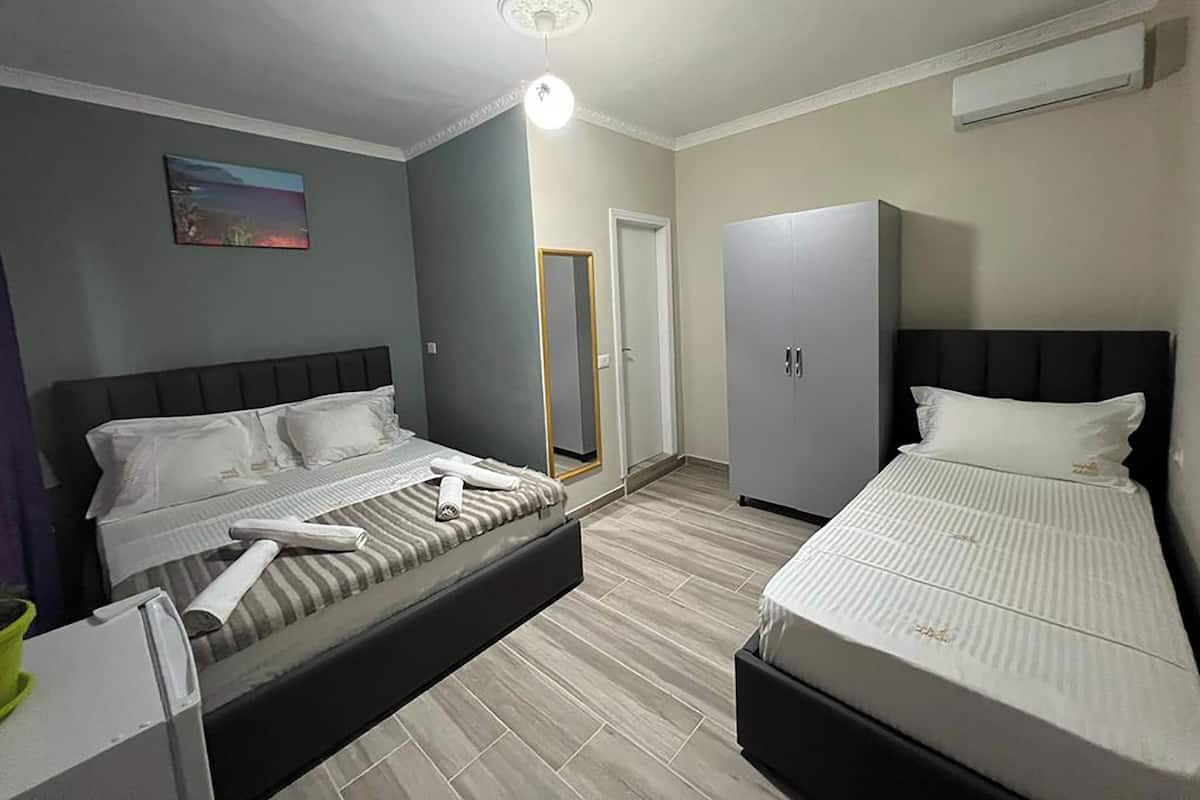 A hotel room with two beds, a wardrobe, a mirror, and a ceiling light.