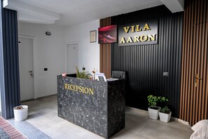 Un mostrador de recepción con un cartel que dice "Vila Aaron" y "Recepción".