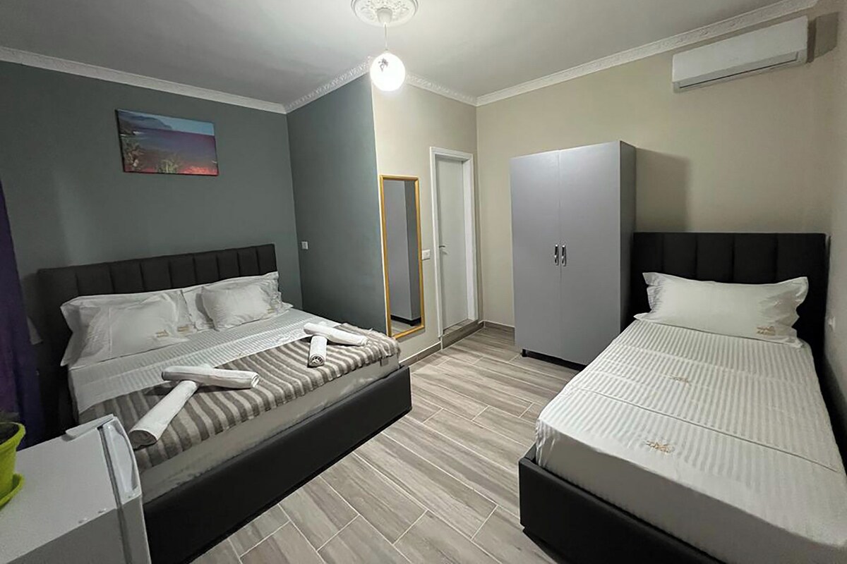 A hotel room with two beds, a wardrobe, a mirror, and a ceiling light.