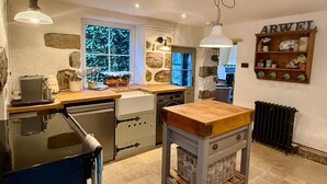 Una cocina con pared de piedra, encimera de madera y lámpara colgante.