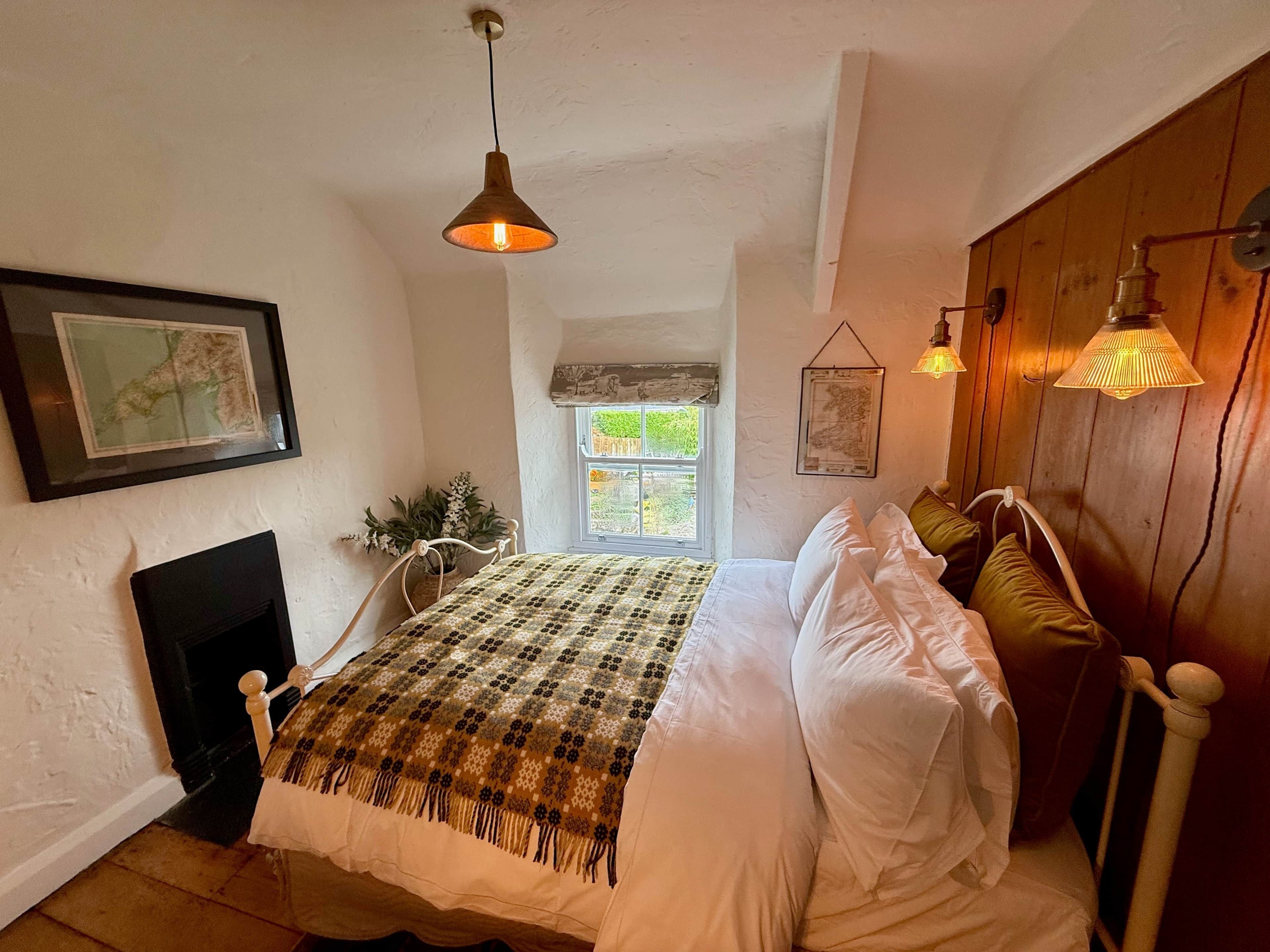 A bedroom with a bed, a fireplace, a window, and wall-mounted lights.