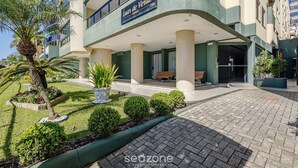 A hotel entrance with a sign reading "Luz de Verão" and a well-maintained outdoor area with plants and a paved walkway. - Apt w Balcony nd Barbecue in Seaside Condom Uar301 (Itapema)