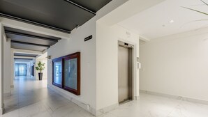 A modern hallway with a marble floor, a potted plant, and an elevator. - Apt w Balcony nd Barbecue in Seaside Condom Uar301 (Itapema)