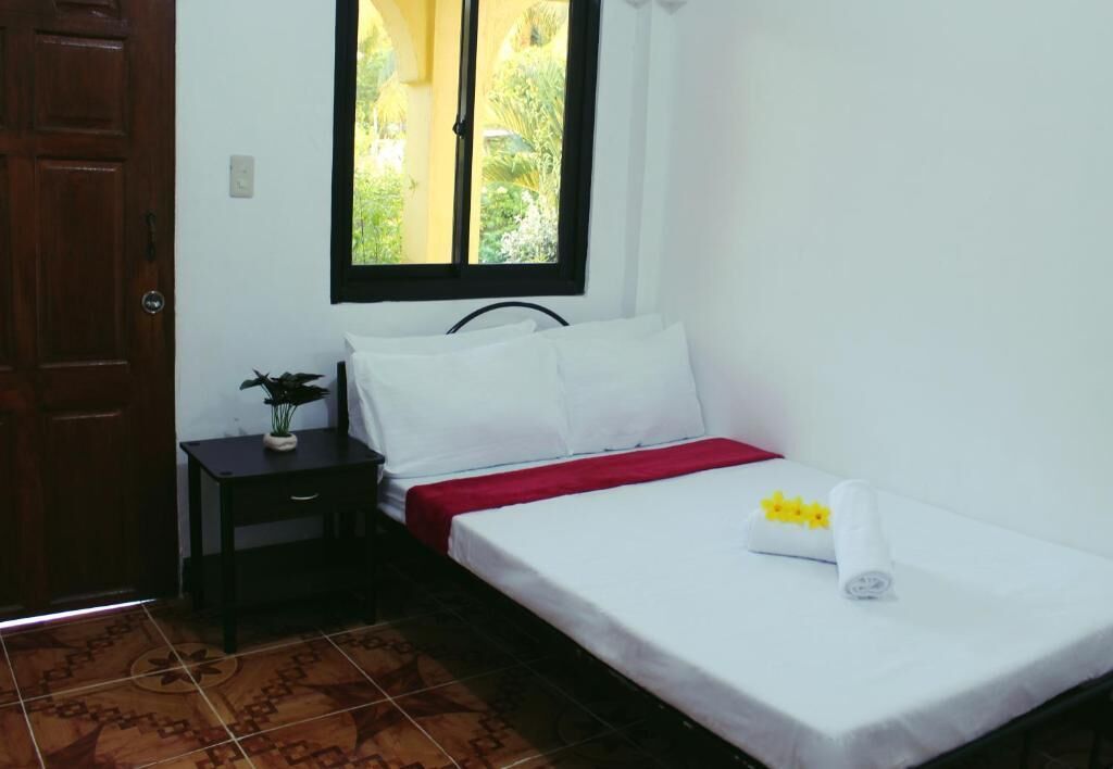 A bedroom with a bed, a nightstand, a window, and a door.