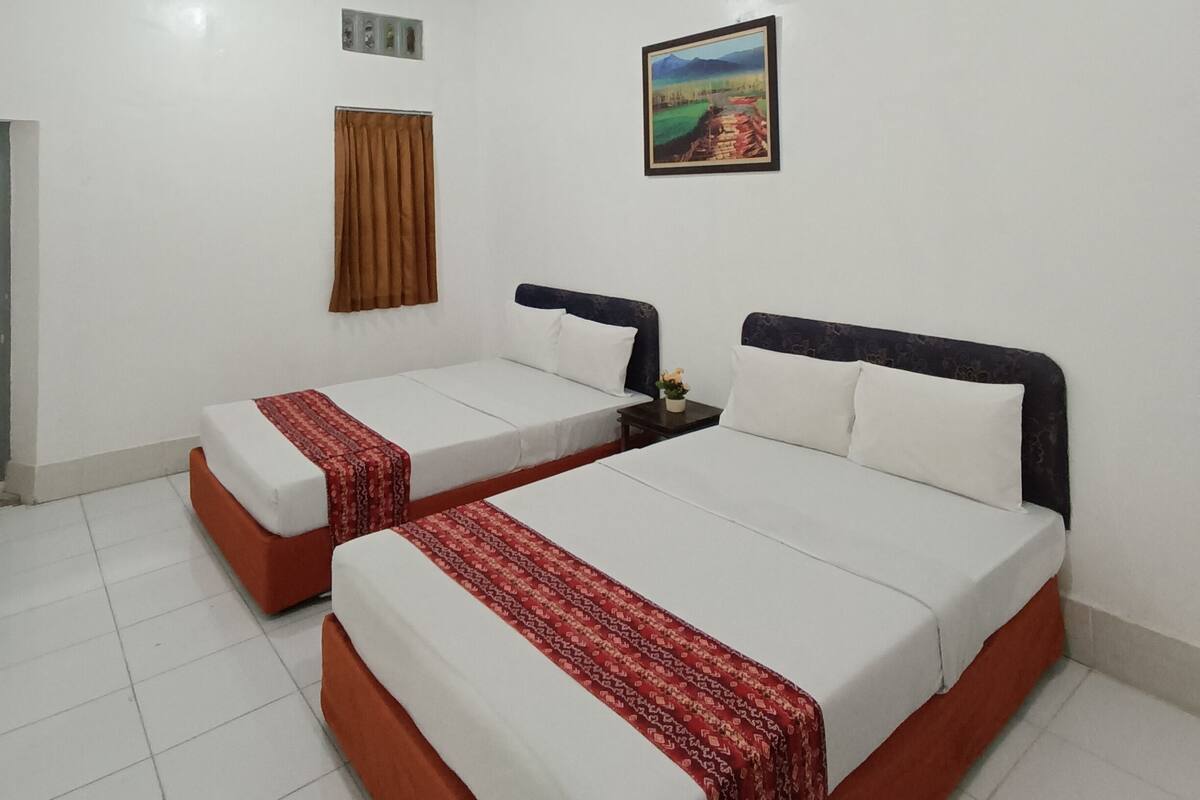 Ein Hotelzimmer mit zwei Einzelbetten, einem Bild an der Wand und einem Fenster mit Vorhängen.