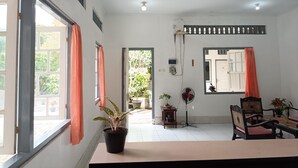 A room with a large window, a fan, and a table with chairs. - Hotel STIPRAM Kaliurang Yogyakarta (Pakem)
