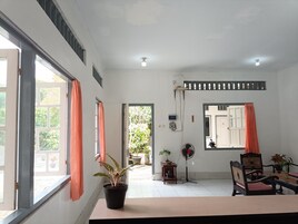 Una habitación con un ventanal grande, un ventilador y una mesa con sillas.