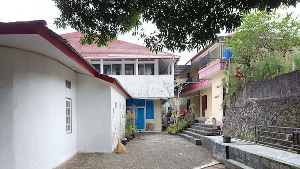 A narrow cobblestone alley with buildings on either side, a staircase leading to a higher level, and a tree providing shade. - Hotel STIPRAM Kaliurang Yogyakarta (Pakem)