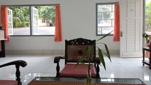 A room with a large window, a chair, a table, and a door. - Hotel STIPRAM Kaliurang Yogyakarta (Pakem)