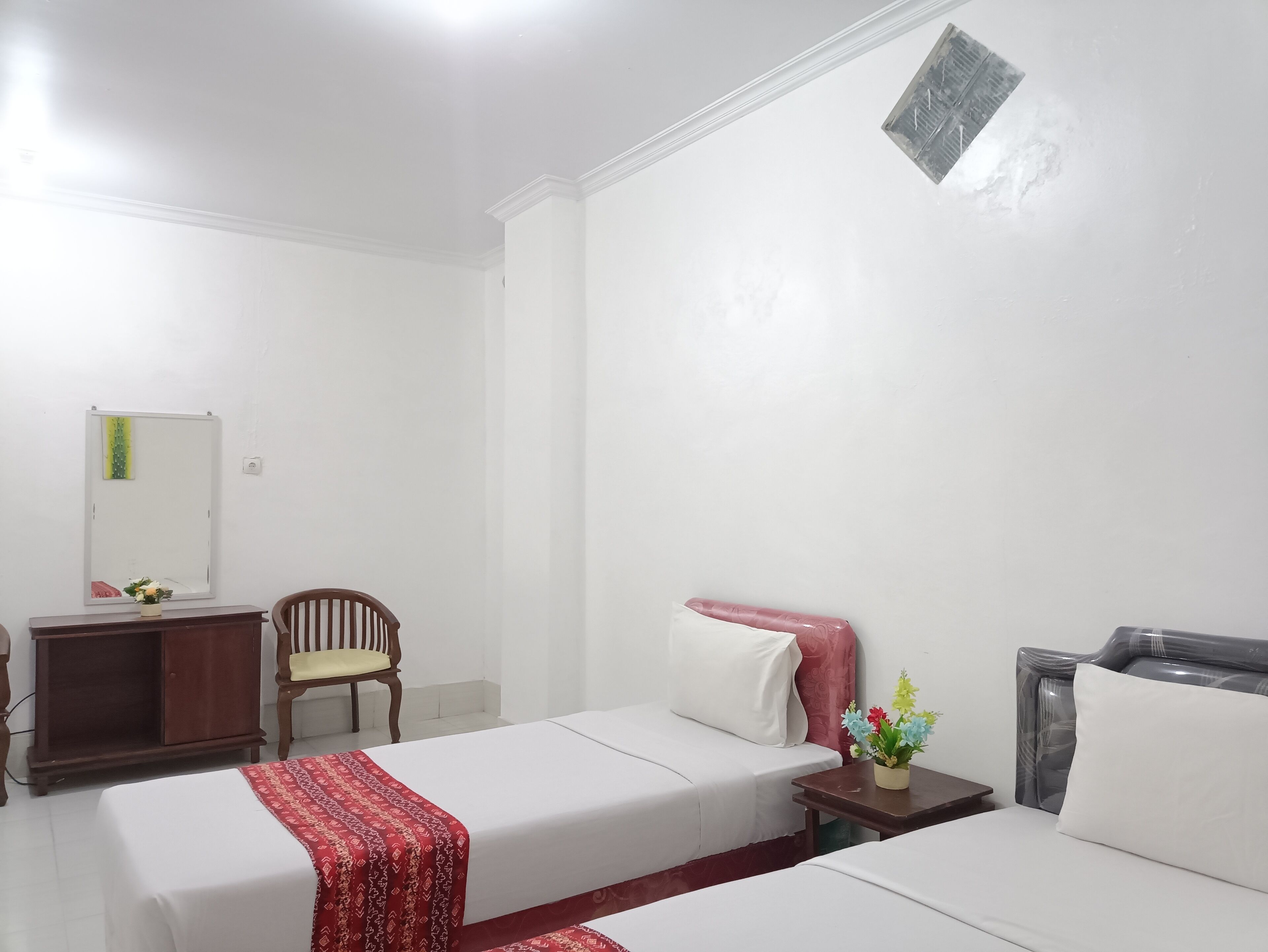 A hotel room with two beds, a desk, a chair, and a mirror.