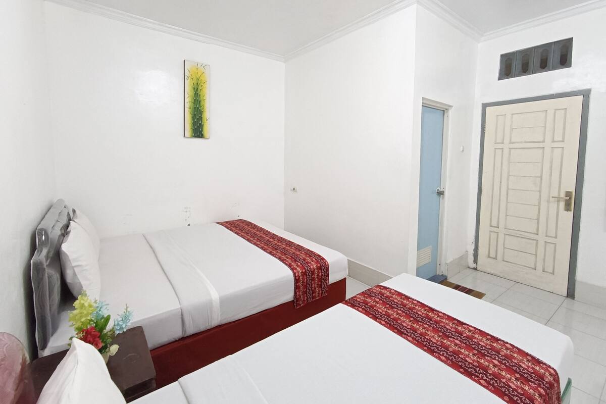 Ein Hotelzimmer mit zwei Betten, einer Tür und einem Wandbild.