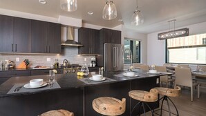 A modern kitchen with dark cabinetry, stainless steel appliances, and a central island with bar stools.