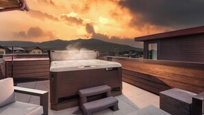 A hot tub on an outdoor deck with a view of mountains and a cloudy sky.