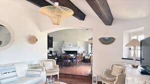 A spacious living room with a white sofa, two armchairs, a coffee table, and a dining area in the background.