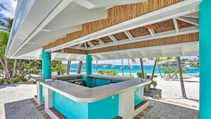 A poolside bar area with a view of the beach and ocean.