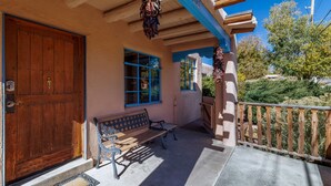 A wooden door, a bench, and a porch with a railing.