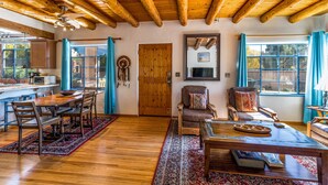 A spacious living room with wooden floors, a dining area with a wooden table and chairs, and a cozy seating area with a sofa and armchairs.