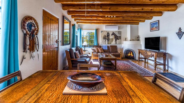 A rustic interior with a wooden dining table, leather seating, a fireplace, and a mounted dreamcatcher.