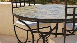 A round table with chairs, a pool, and lounge chairs in the background. - Domaine Robert (Rognes)