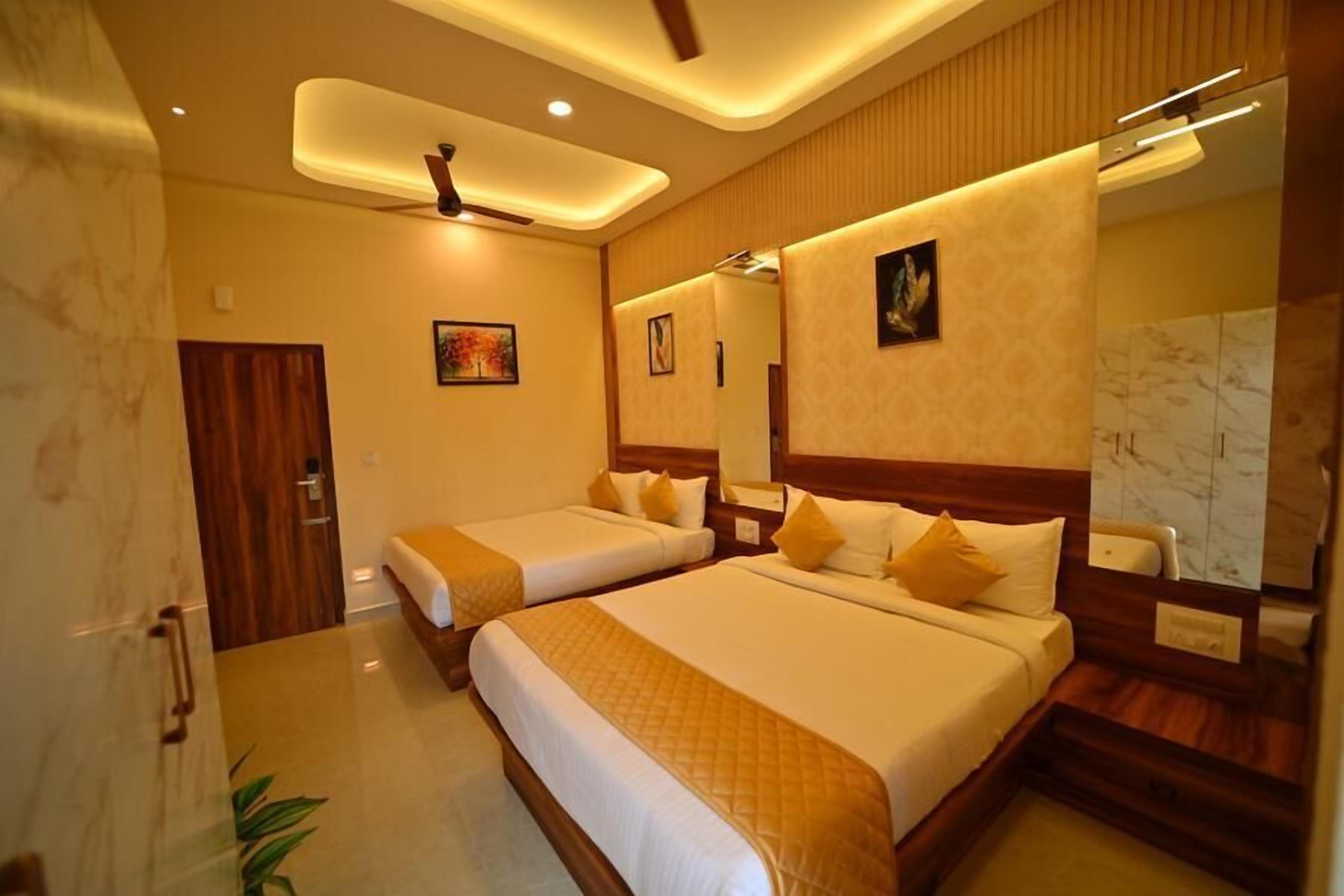 A hotel room with two beds, a ceiling fan, and a large mirror.